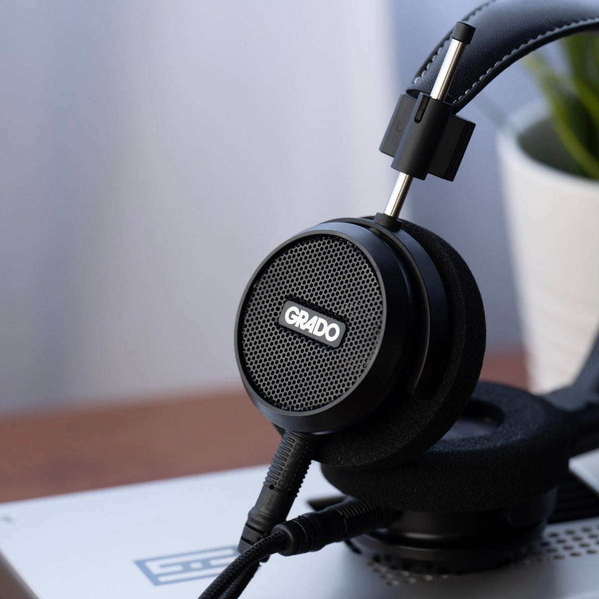 Grado Signature S150 headphones resting on a desktop DAC